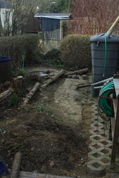 24.03.: Rasengittersteine verlegt, Kübel eingegraben, was man wegen der Thujenstämme nicht sieht. Also schnappet ich mir eine der verrosteten Sägen aus dem Müllhaufen.