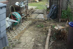 Von der anderen Seite: Gießkannen auf Trockenstab, Schlauchwagen in der Nähe des Anschlusses.